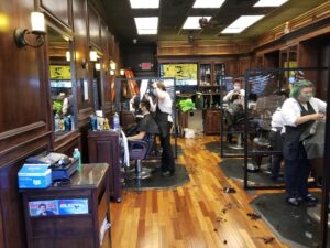 A barber shop with many people working on their hair.