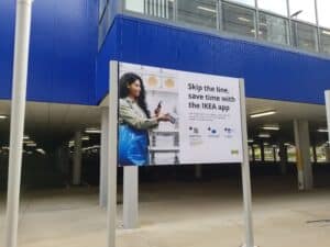 A woman is standing in front of a blue building with a sign.