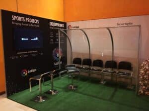 A booth with chairs and a tv screen.